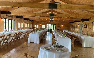 View of wedding seating inside a blonde-wood post-and-beam event hall.