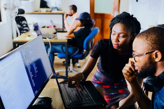 Two people looking at a laptop in a classroom